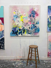 Load image into Gallery viewer, Offbeat original painting by Tania LaCaria displayed on a white wall in the artist&#39;s studio with a traditional wooden stool in the foreground.
